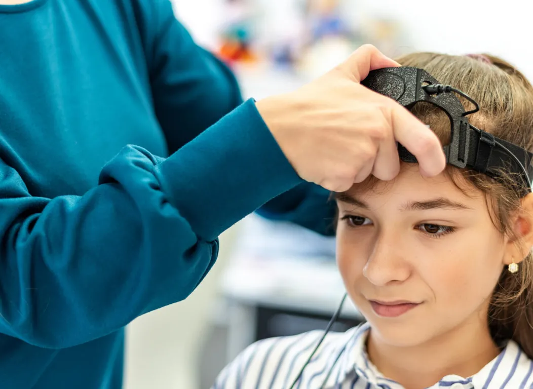 Neurofeedback EEG test being performed by therapist and young female child