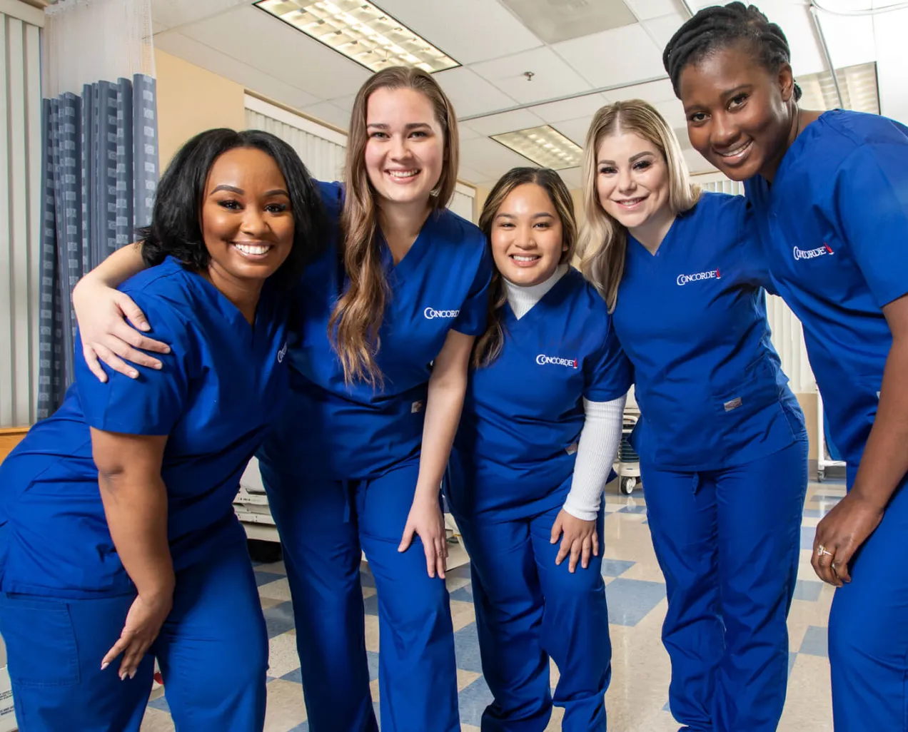 Concorde nursing students in scrubs pose together in a clinical lab, representing Oregon workforce training partnerships