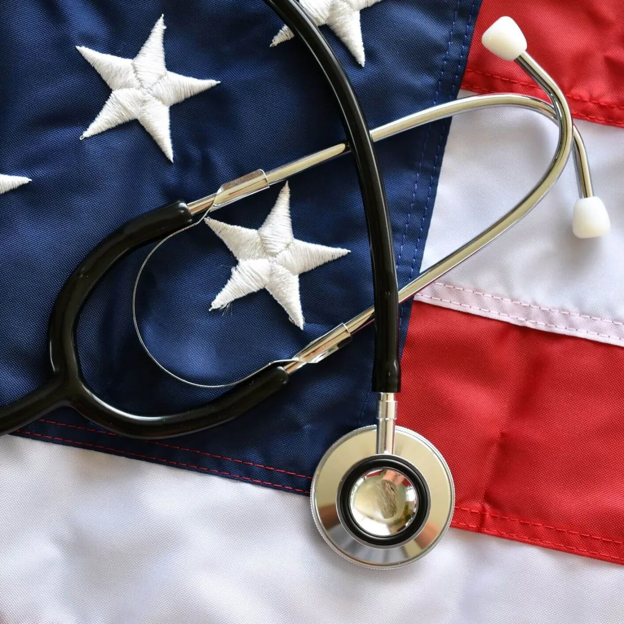 A black stethoscope resting on a folded American flag, representing healthcare career training funded through Concorde military tuition support and VA benefits.