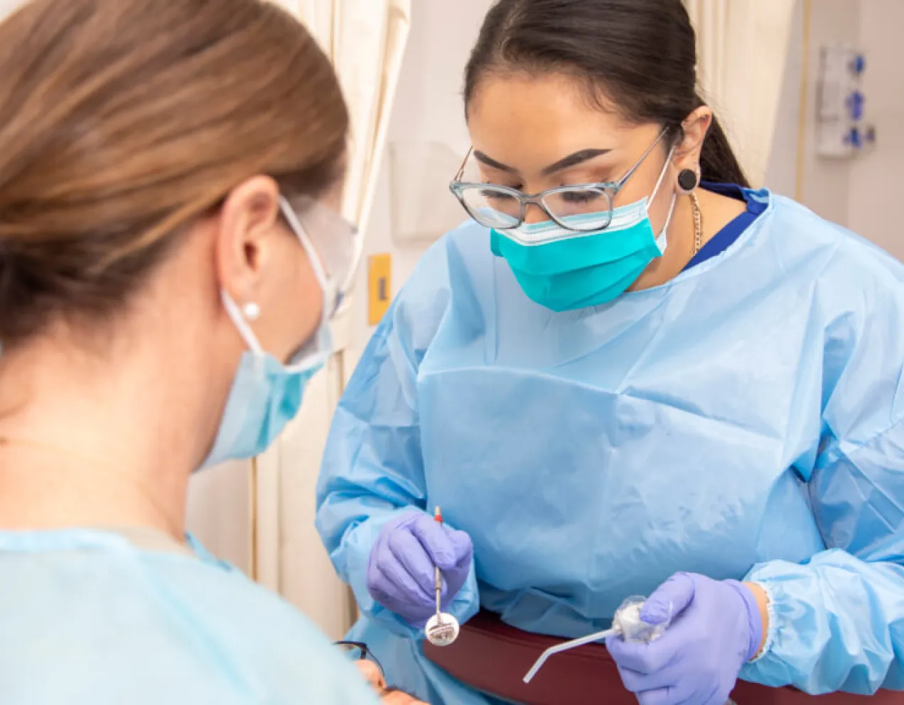 Dental Assistant in scrubs calms patient during procedure with dentist