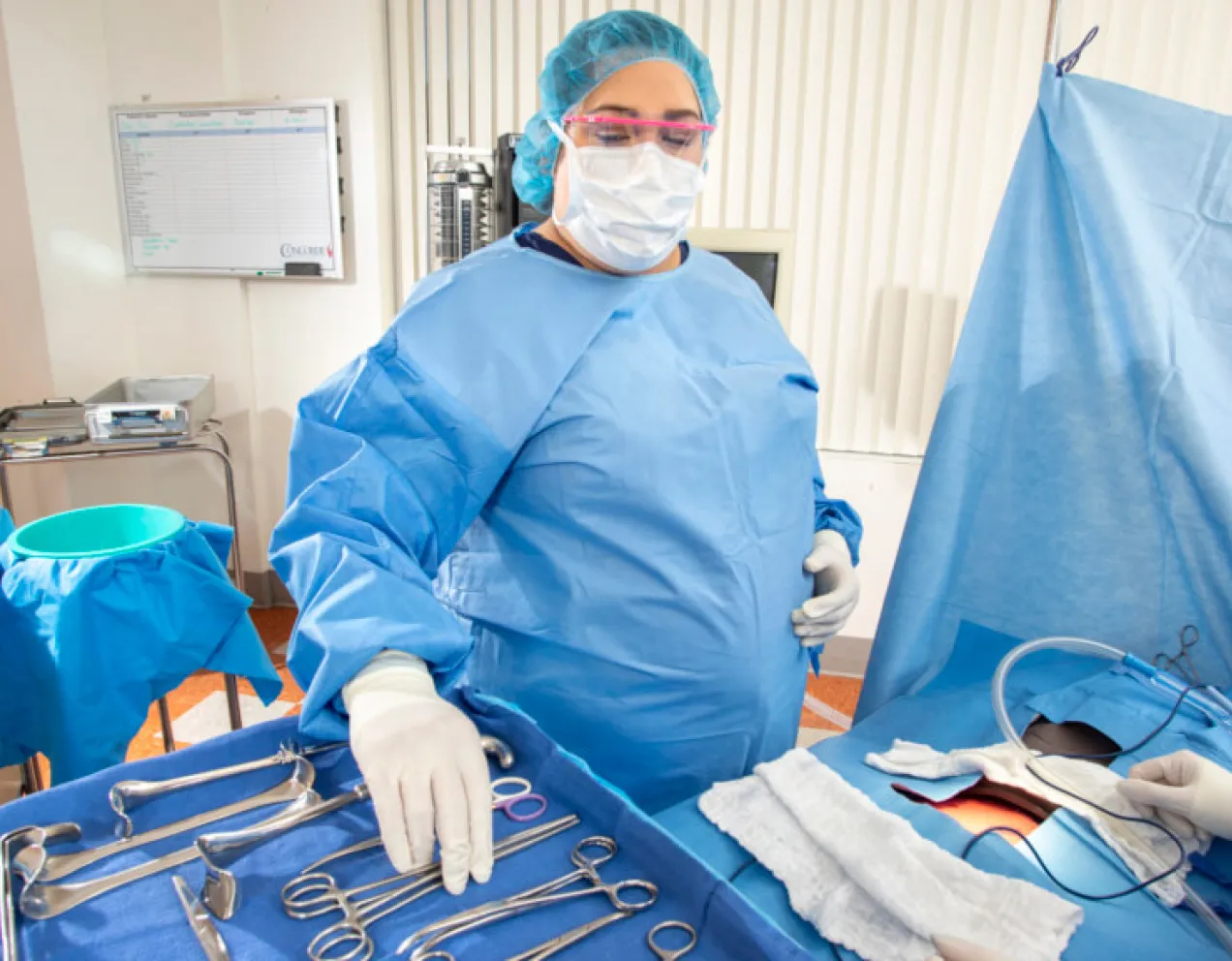 Surgical Technologist in scrubs performing the requirements of hands on training in the OR