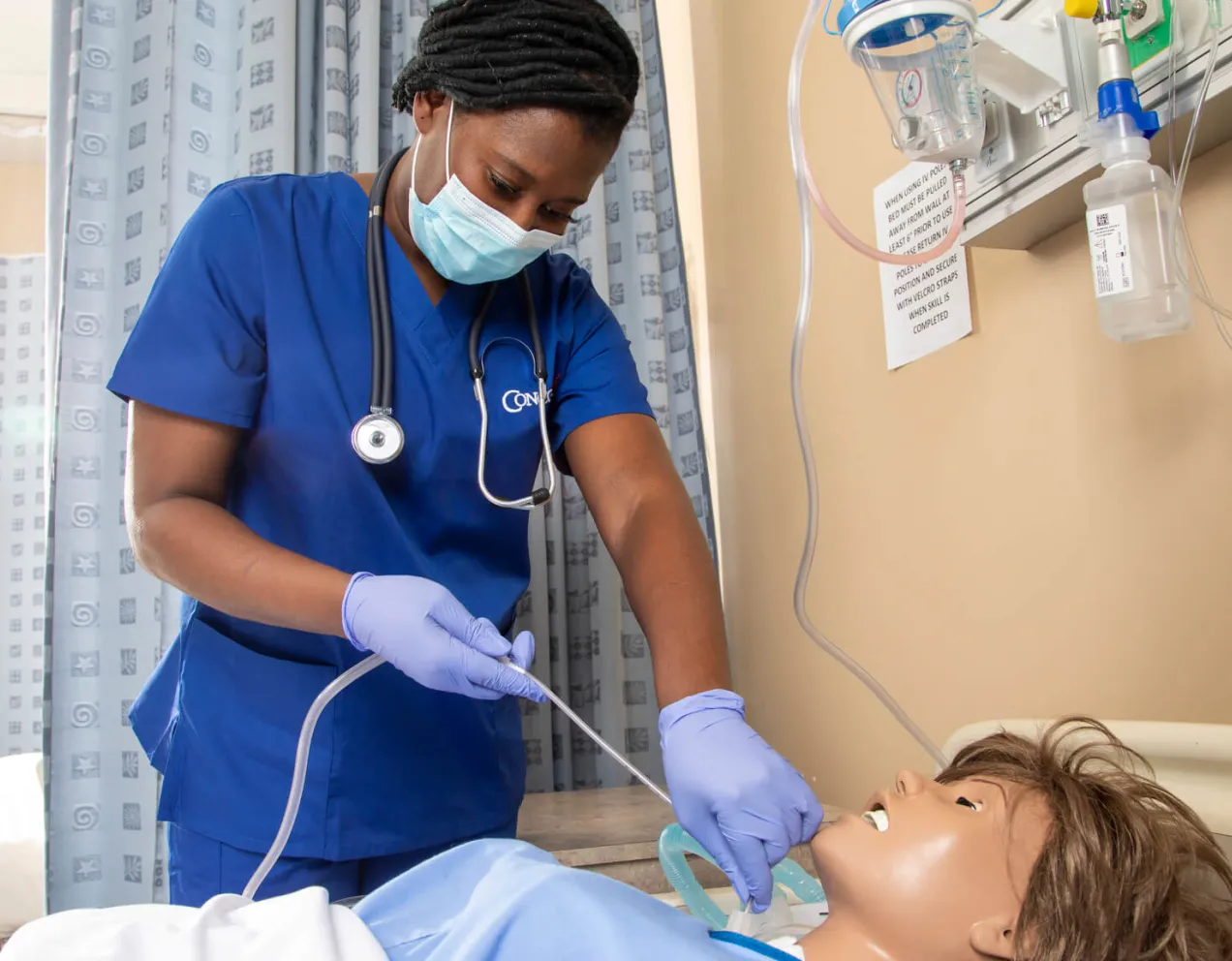 Nursing student practicing skills on a simulation mannequin.