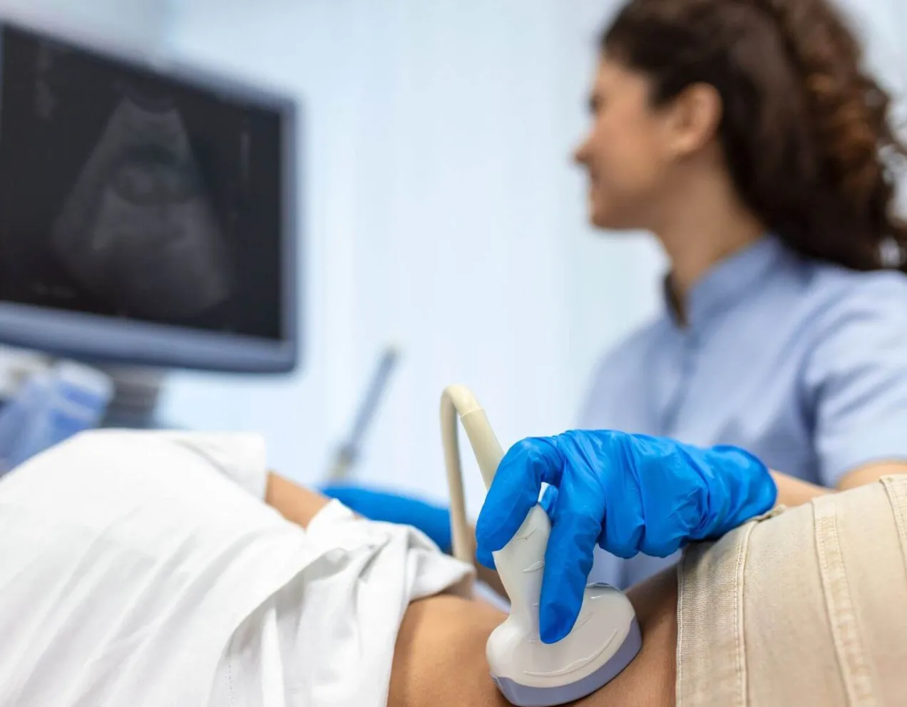 Sonographer conducting abdominal ultrasound with patient while monitoring live scan results.
