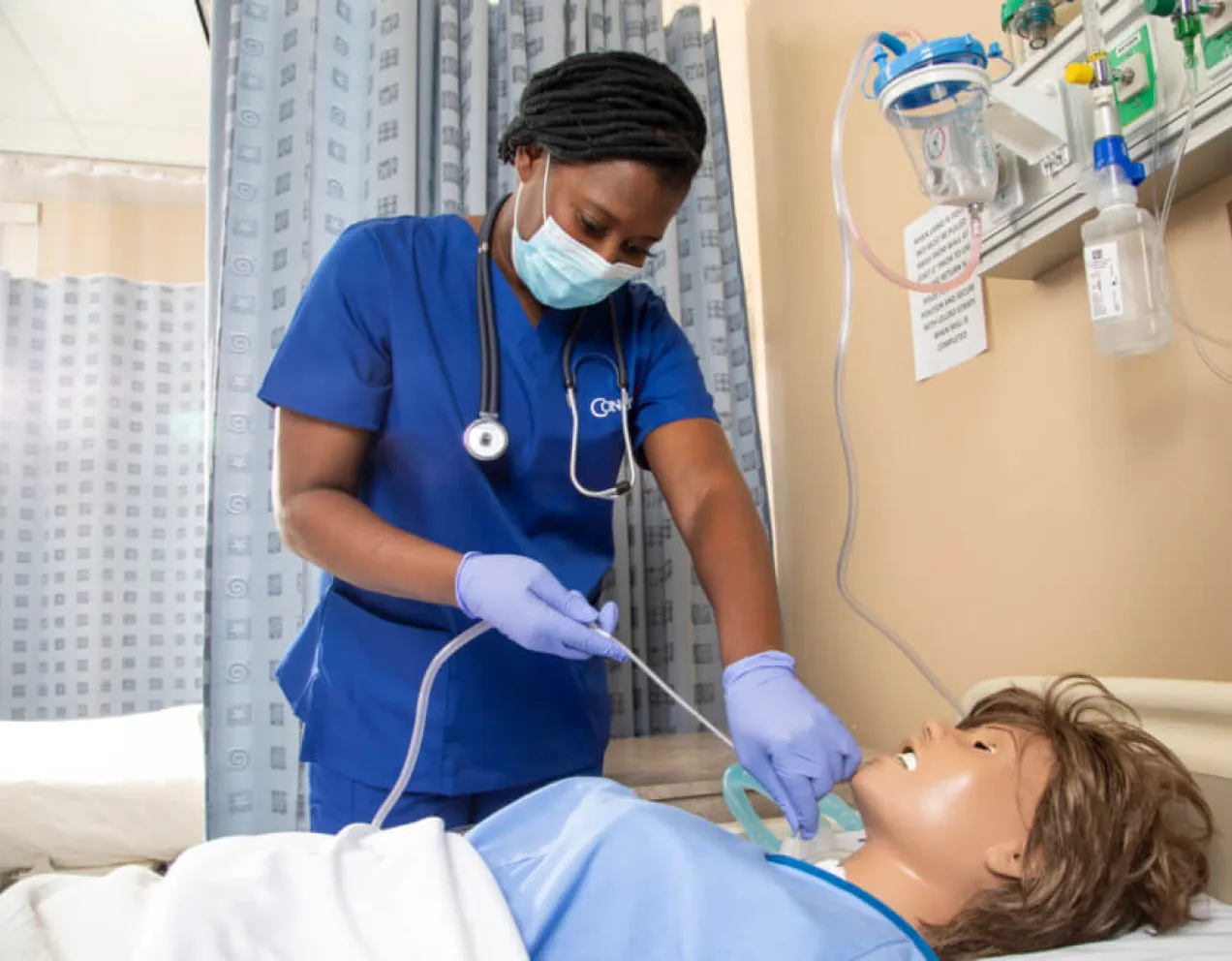 Nursing student performing suctioning procedure on training manikin in lab
