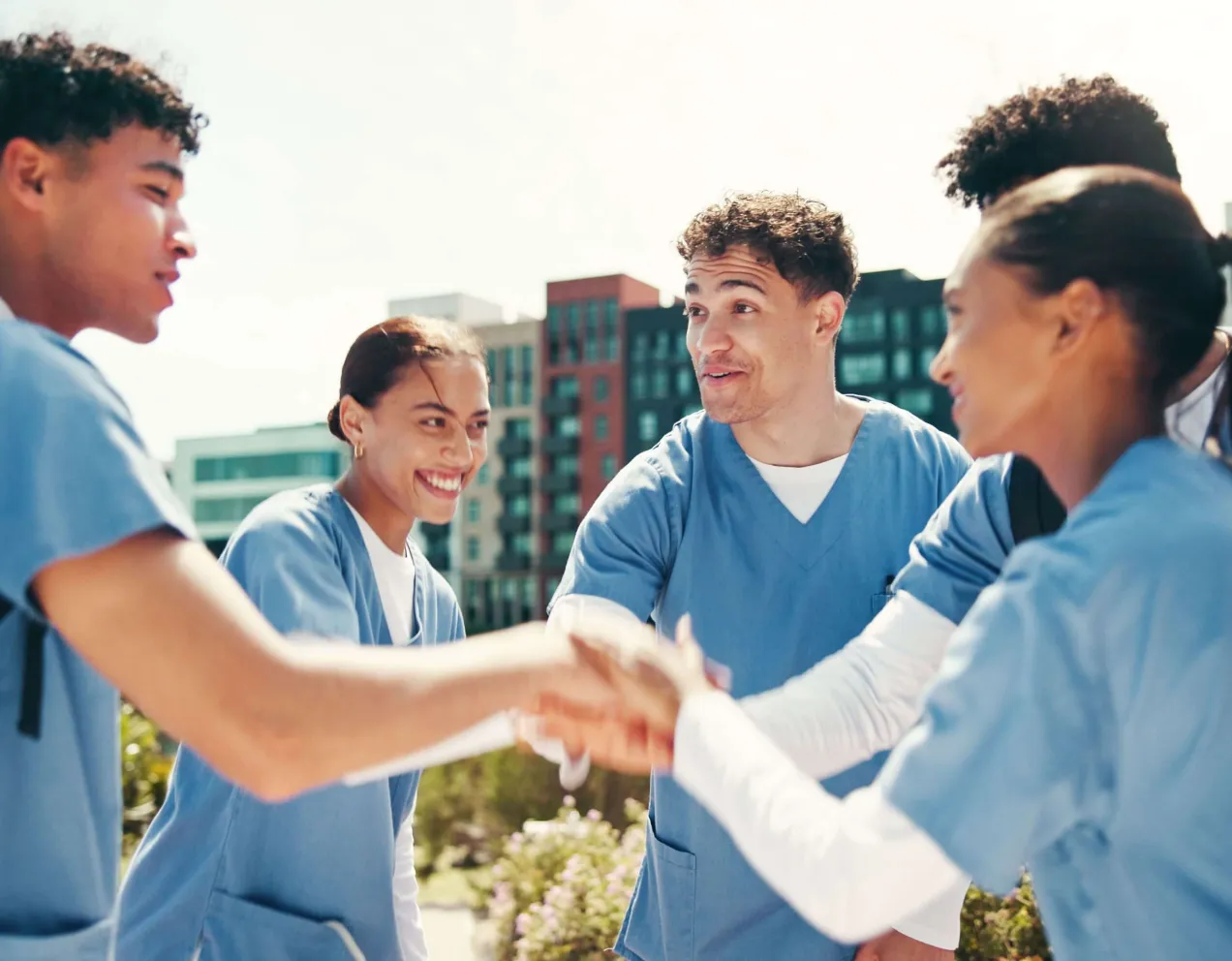 A group of nursing students in scrubs standing together and offering each other encouragement and peer support.