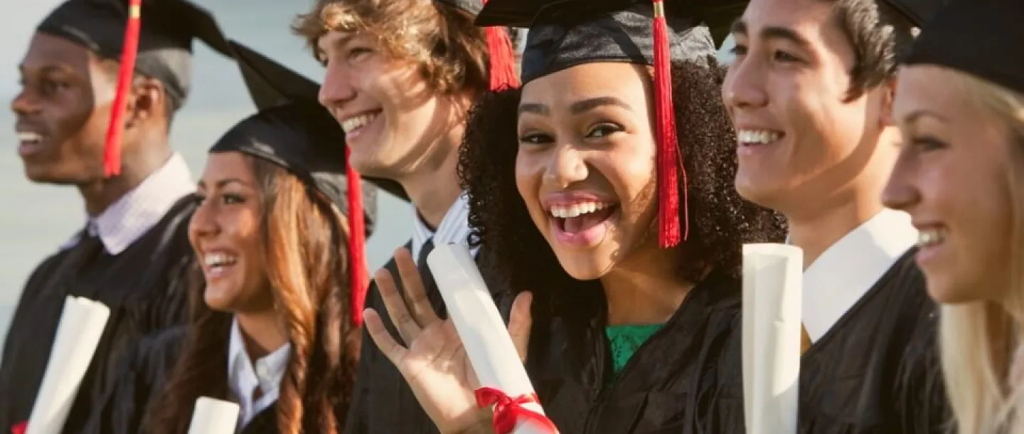 Smiling graduates holding diplomas and degrees
