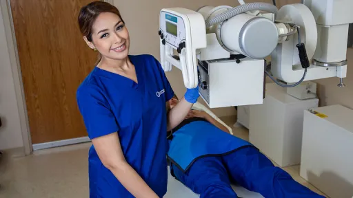 A radiology tech prepares a patient on table for an x-ray.