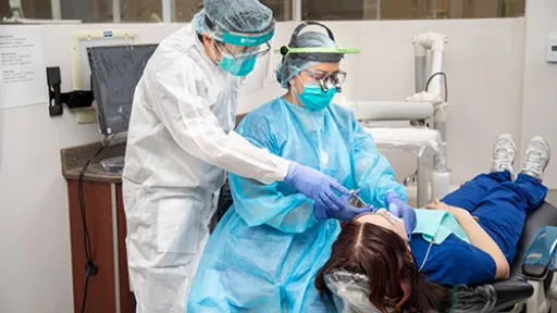 A dental hygienist learning how to administer local anesthetic to patient under supervision of instructor.