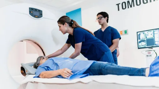 Radiologic technologists preparing a patient for a CT scan in a hospital setting