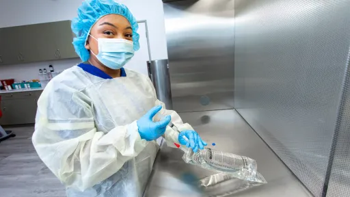 Pharmacy technician preparing IV medication in a sterile compounding environment.