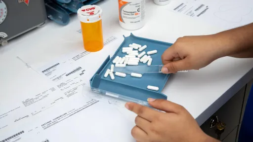Pharmacy technician sorting pills on a tray as part of daily duties in a pharmacy setting.