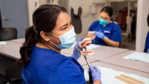 Dental assisting student practicing with a dental model during hands-on training in the classroom.