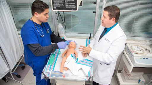 Instructor shares respiratory therapy education requirements with student in lab setting.