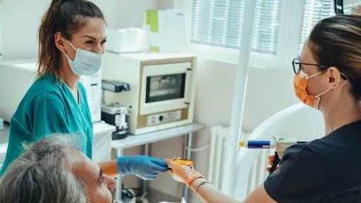 A female dental assistant in green scrubs handing dental instruments to dentist for dental impressions dental assistant responsibilities