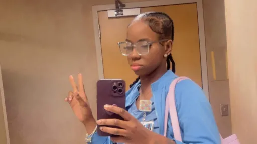 Antwonette taking a selfie in light blue scrubs and light pink bag