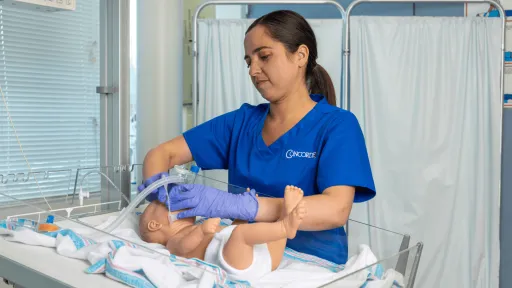 A female respiratory therapist wearing blue scrubs uses CPAP machine on infant to help infant breathe