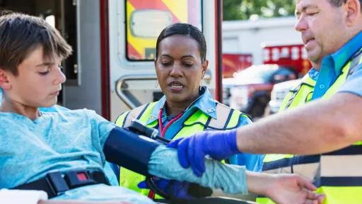 Two paramedics caring for a teenage boy on a stretcher.