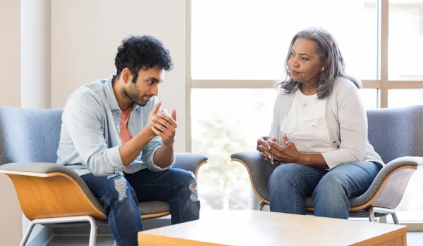 A young man speaks with his mental health provider about an experience that caused a negative emotional reaction.