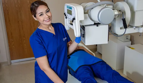 A radiology tech prepares a patient on table for an x-ray.