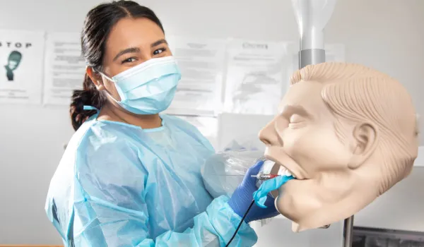 Dental Assistant cleaning the mouth of a dental manekin.