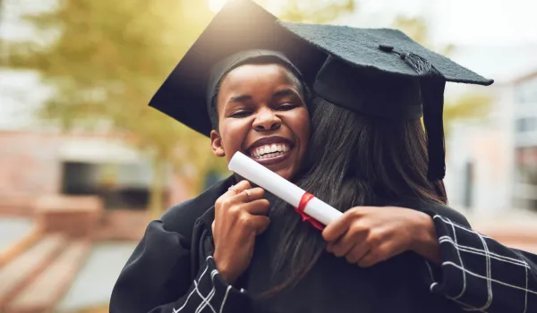 Graduate in cap and gown getting a celebratory hug.