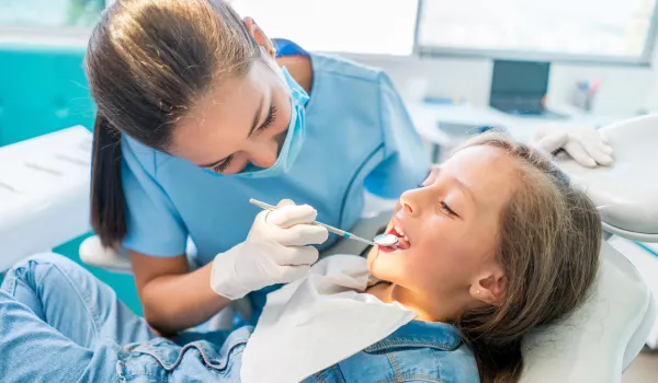 Day in the life of a dental assistant as they performs oral-cavity inspection on child with mouth-mirror