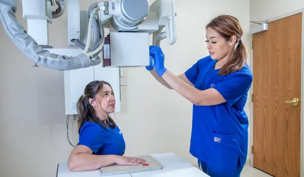 A radiology tech adjusts an x-ray machine on a patient's hand.