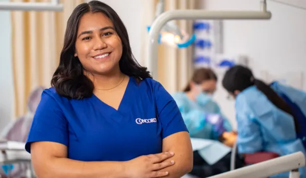 Dental Assistant in scrubs smiles with confidence