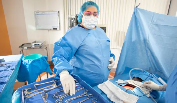 Surgical Technologist in scrubs performing the requirements of hands on training in the OR