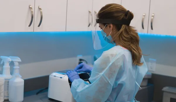 Sterile Processing Technician wearing PPE sterilizing medical equipment at the hospital.