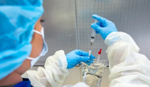 Pharmacy technician preparing medication with syringe and IV bag in sterile environment, showcasing certification skills.