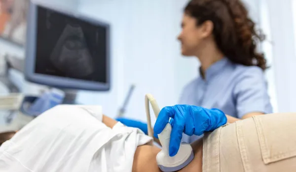 Sonographer conducting abdominal ultrasound with patient while monitoring live scan results.