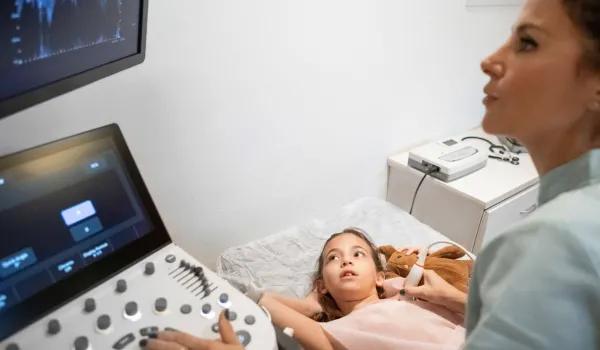 Cardiovascular sonographer performing heart ultrasound on young patient, illustrating diagnostic imaging in cardiac care.