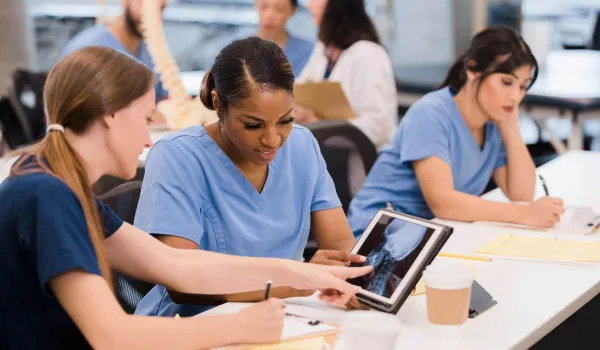 Radiologic technology students review spinal X-ray on tablet during class, preparing for hands-on healthcare careers