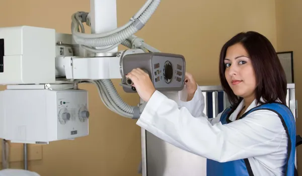 Radiologic technologist adjusting X-ray equipment before a diagnostic imaging procedure