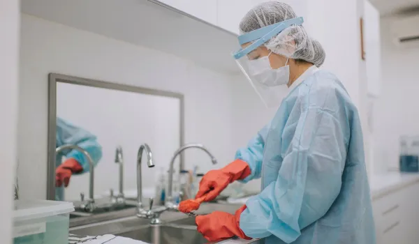 Sterile processing technician cleaning surgical tools at a sink, representing job responsibilities and outlook