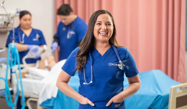 Concorde student smiling as others study respiratory therapy in the background