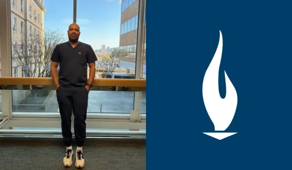 JR in navy blue scrubs standing proudly in the hallway of a hospital