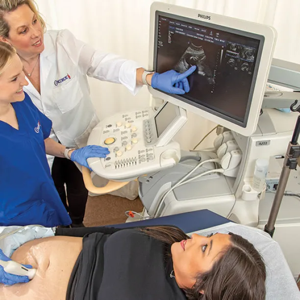 Diagnostic medical sonographer performs ultrasound on expecting mother.