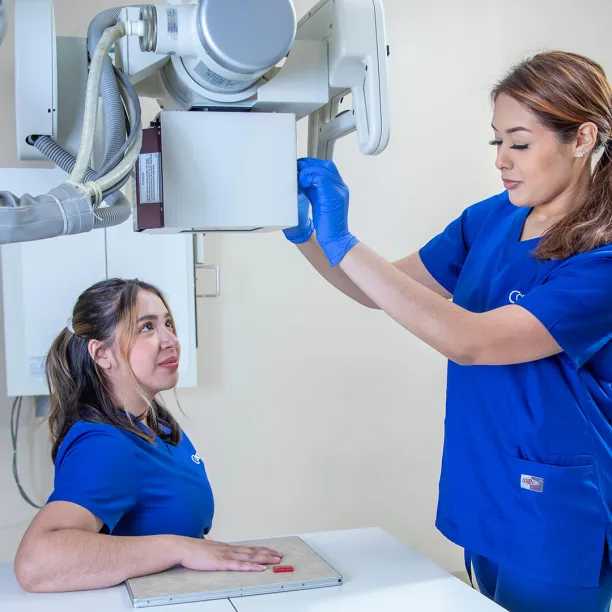 A radiology tech adjusts an x-ray machine on a patient's hand.