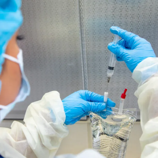 Pharmacy technician preparing medication with syringe and IV bag in sterile environment, showcasing certification skills.