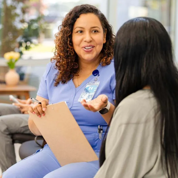 Medical office specialist speaking with patient in a clinic waiting room, highlighting the role's communication and support duties