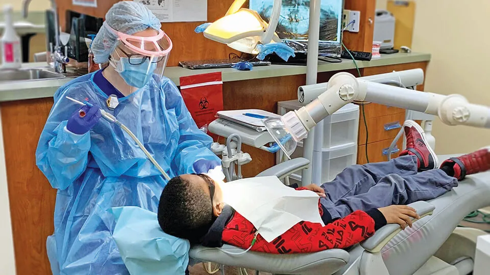 A dental hygienist performs a routine cleaning on young male patient. A dental hygienist performs a routine cleaning on young male patient.
