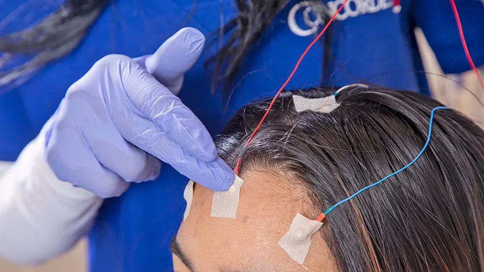 A neurodiagnostic technologist puts electrodes on patient's forehead. A neurodiagnostic technologist puts electrodes on patient's forehead.