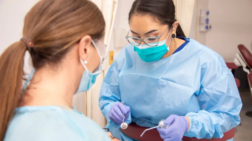 Dental Assistant in scrubs calms patient during procedure with dentist