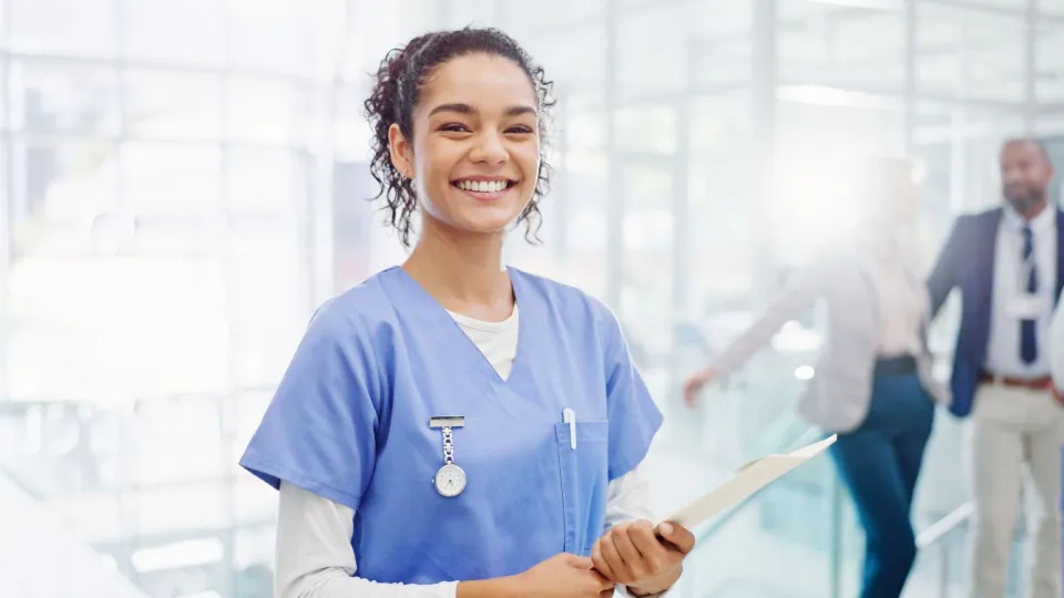 Medical assistant holding a clipboard and smiling in a modern healthcare facility. Medical assistant holding a clipboard and smiling in a modern healthcare facility.