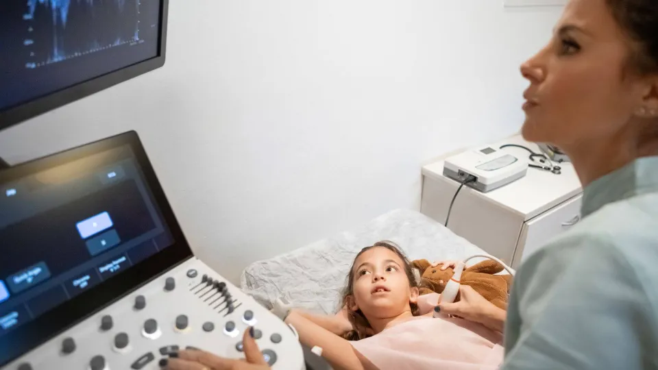 Cardiovascular sonographer performing heart ultrasound on young patient, illustrating diagnostic imaging in cardiac care. Cardiovascular sonographer performing heart ultrasound on young patient, illustrating diagnostic imaging in cardiac care.