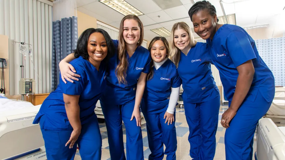 Concorde nursing students in scrubs pose together in a clinical lab, representing Oregon workforce training partnerships Concorde nursing students in scrubs pose together in a clinical lab, representing Oregon workforce training partnerships