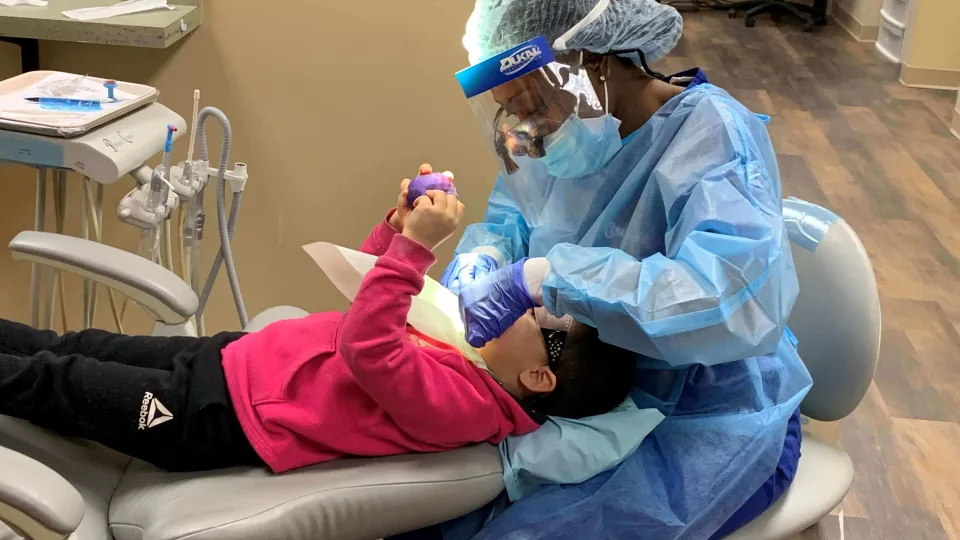 Dental Hygiene student performing dental cleaning on child under Dentist supervision Dental Hygiene student performing dental cleaning on child under Dentist supervision