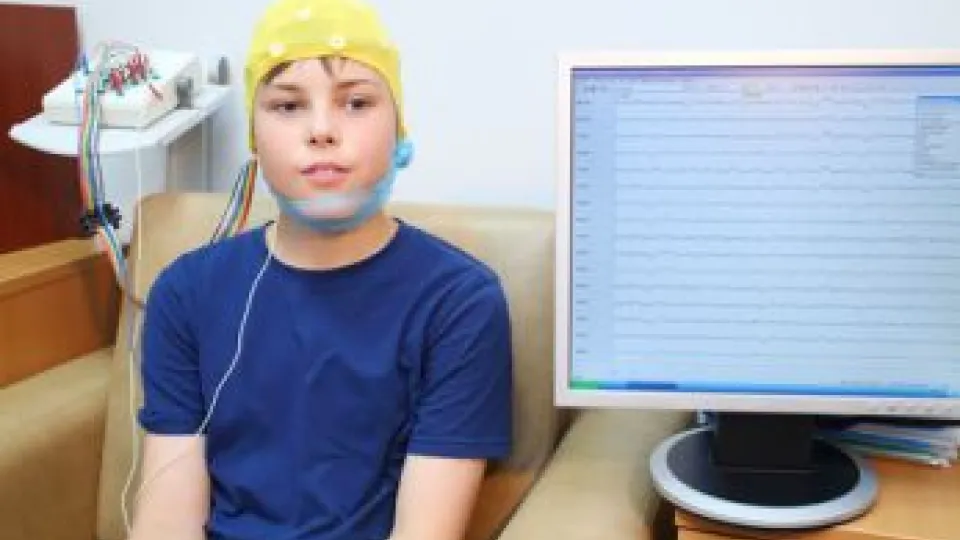 Boy in a special cap during electroencephalography next to the monitor with readings Boy in a special cap during electroencephalography next to the monitor with readings